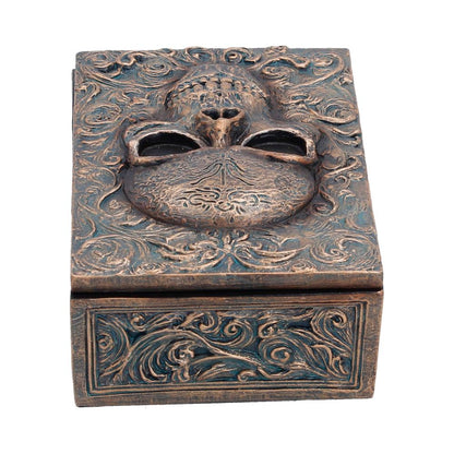Small black box with intricate embossed design, labeled "Treasured Remains," by Nemesis Now, measuring 5.6cm.